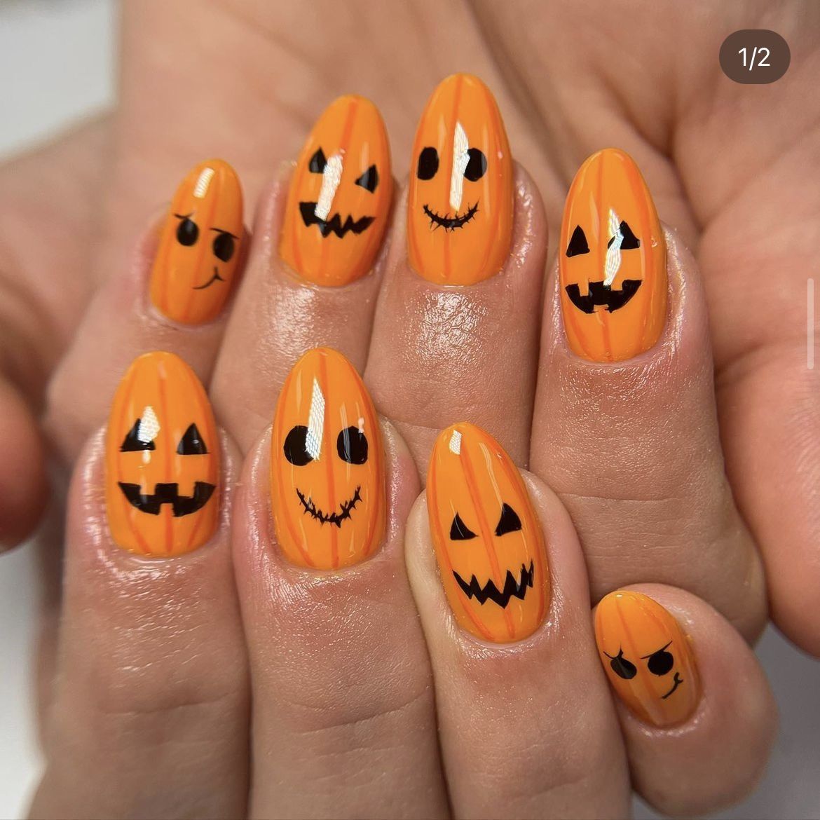 Close-up of fingernails painted orange, each with a different black jack-o'-lantern face.