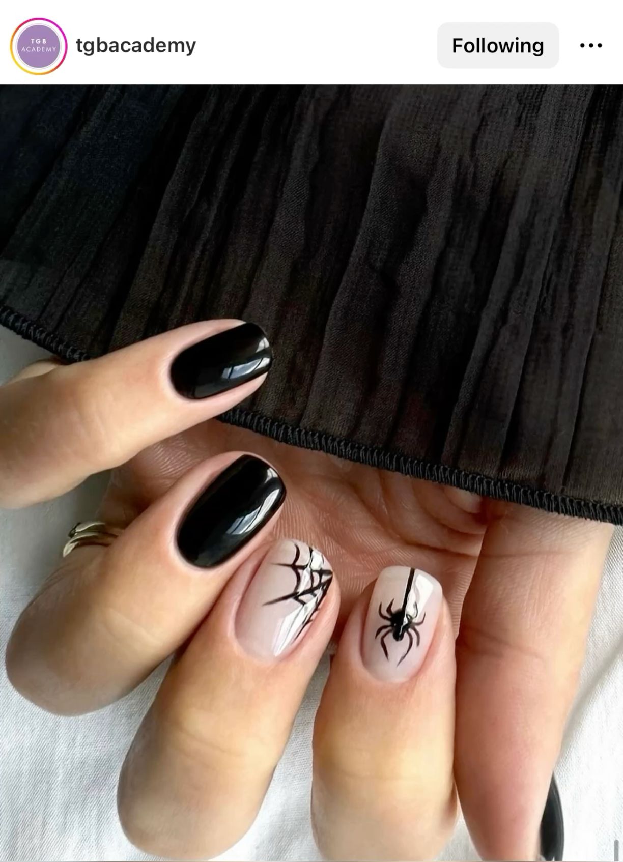 Close-up of a hand with short, oval-shaped nails. Two nails are solid black, and two nails have a neutral base with black…