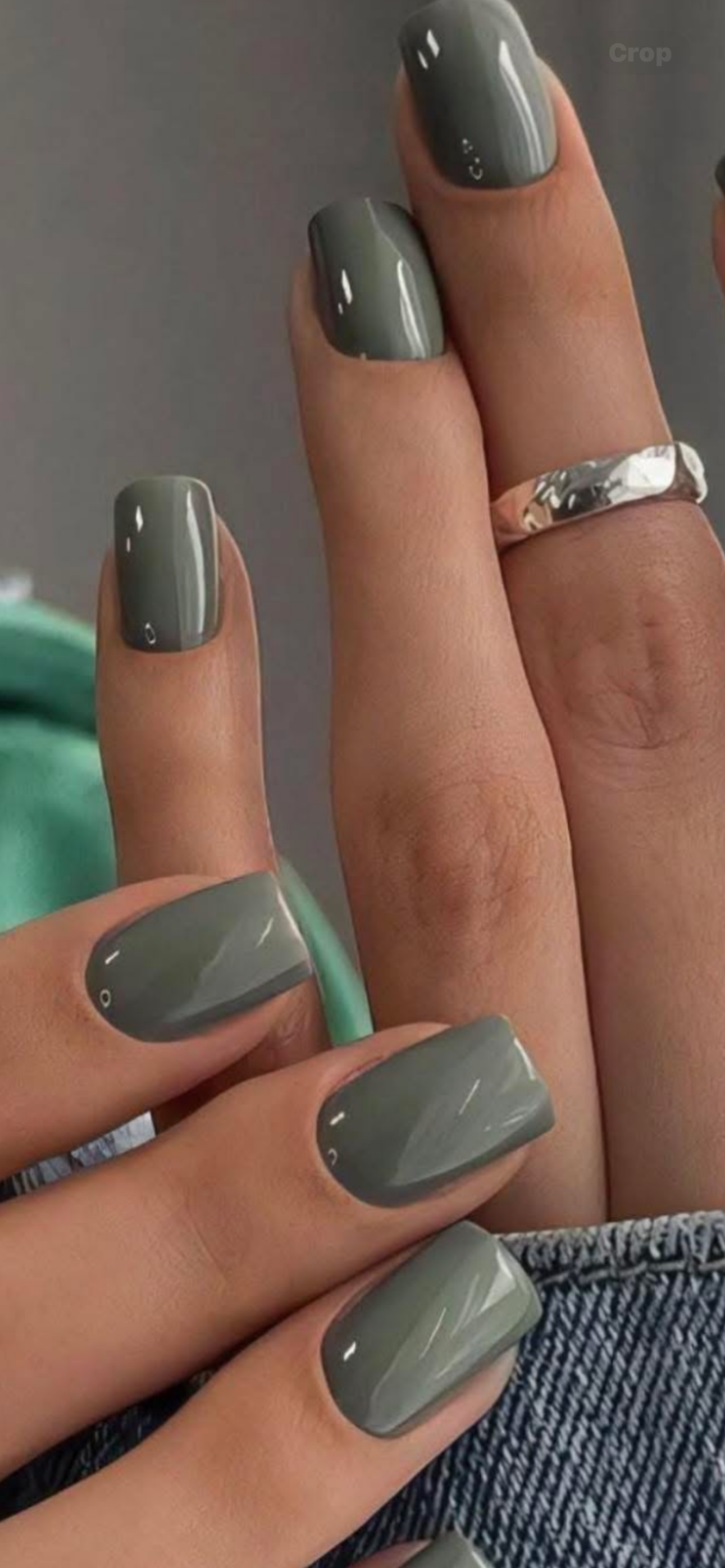 Close up of a hand showing nails painted in solid military green polish with a square shape.