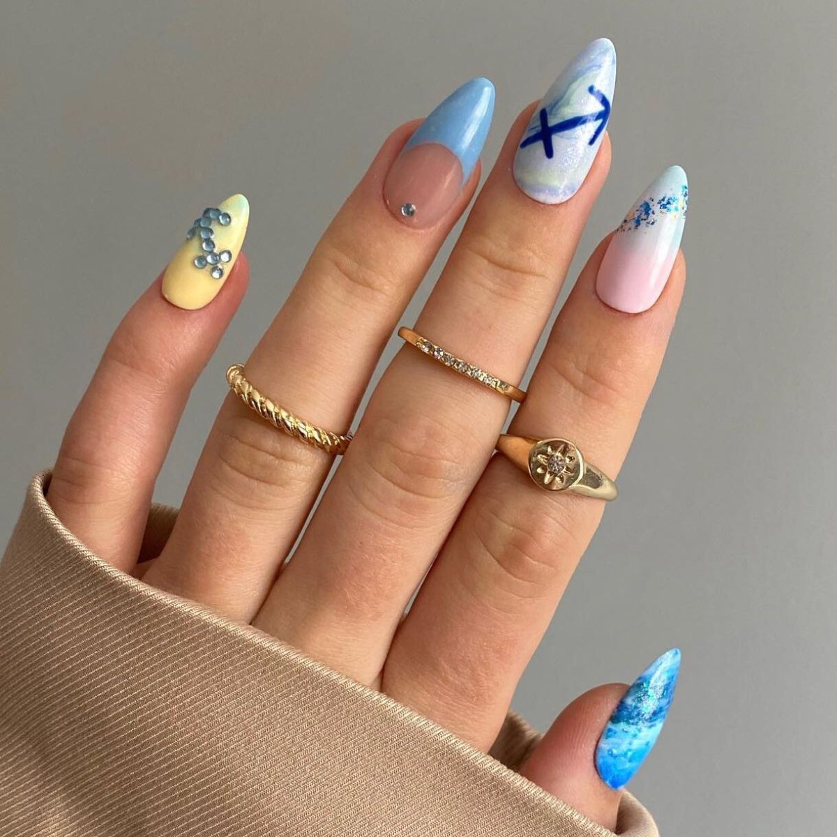 Almond-shaped nails with light blue, yellow, pink, and white polish.