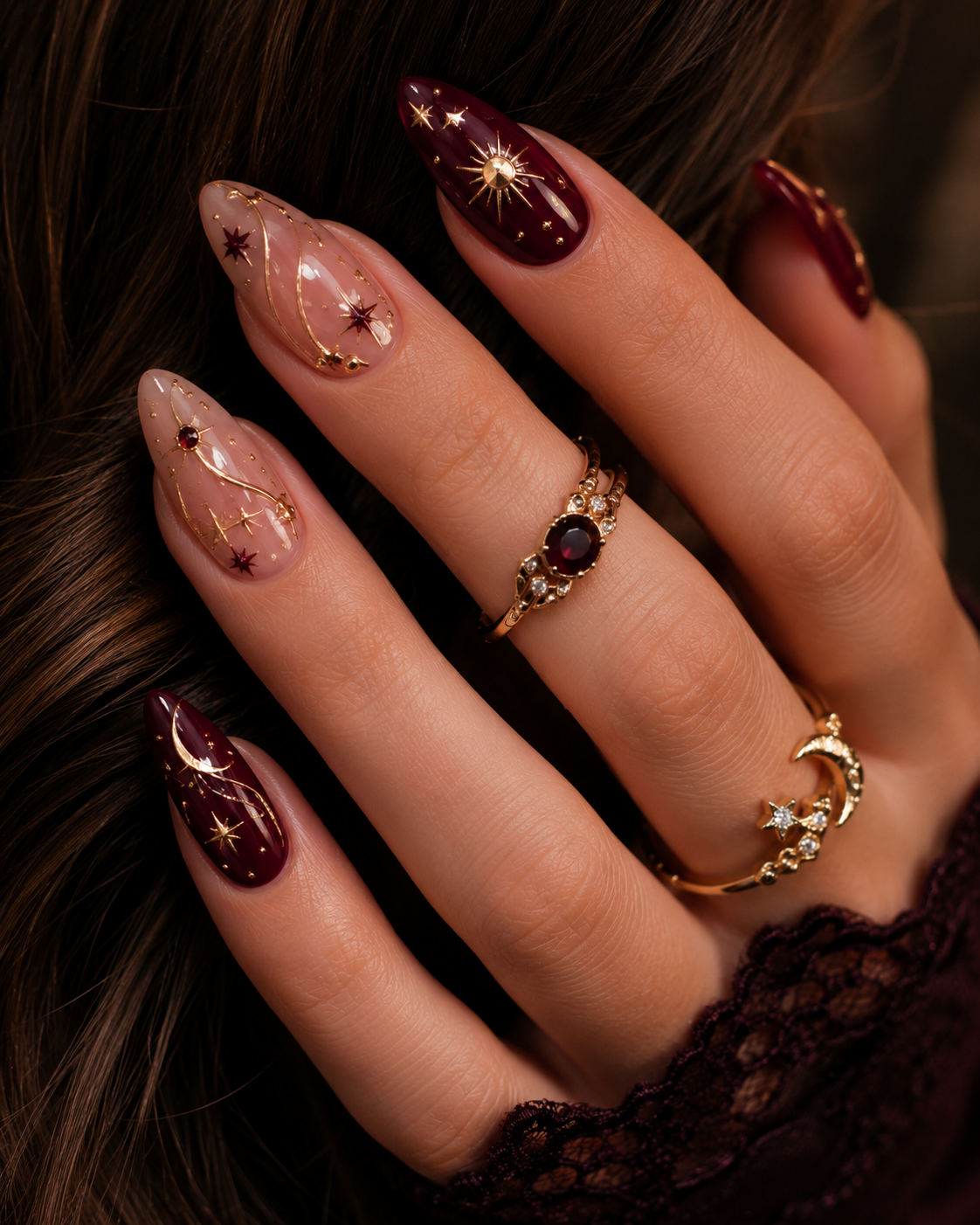 Close-up of a hand with long, almond-shaped nails featuring celestial designs.