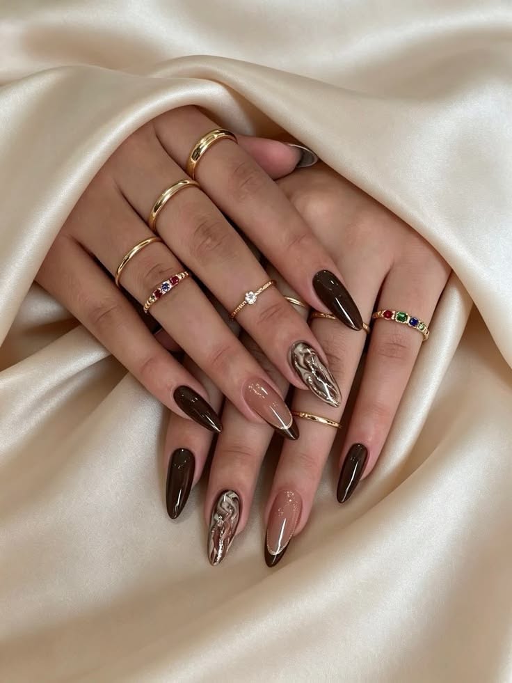 Long almond-shaped acrylic nails. Some are solid dark brown and some are nude with brown French tips.