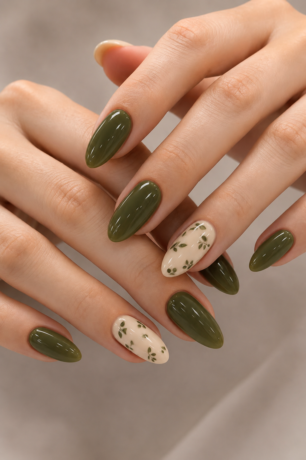 Close up of manicured hands with alternating military green and cream nails. The cream nails feature a subtle leafy pattern.