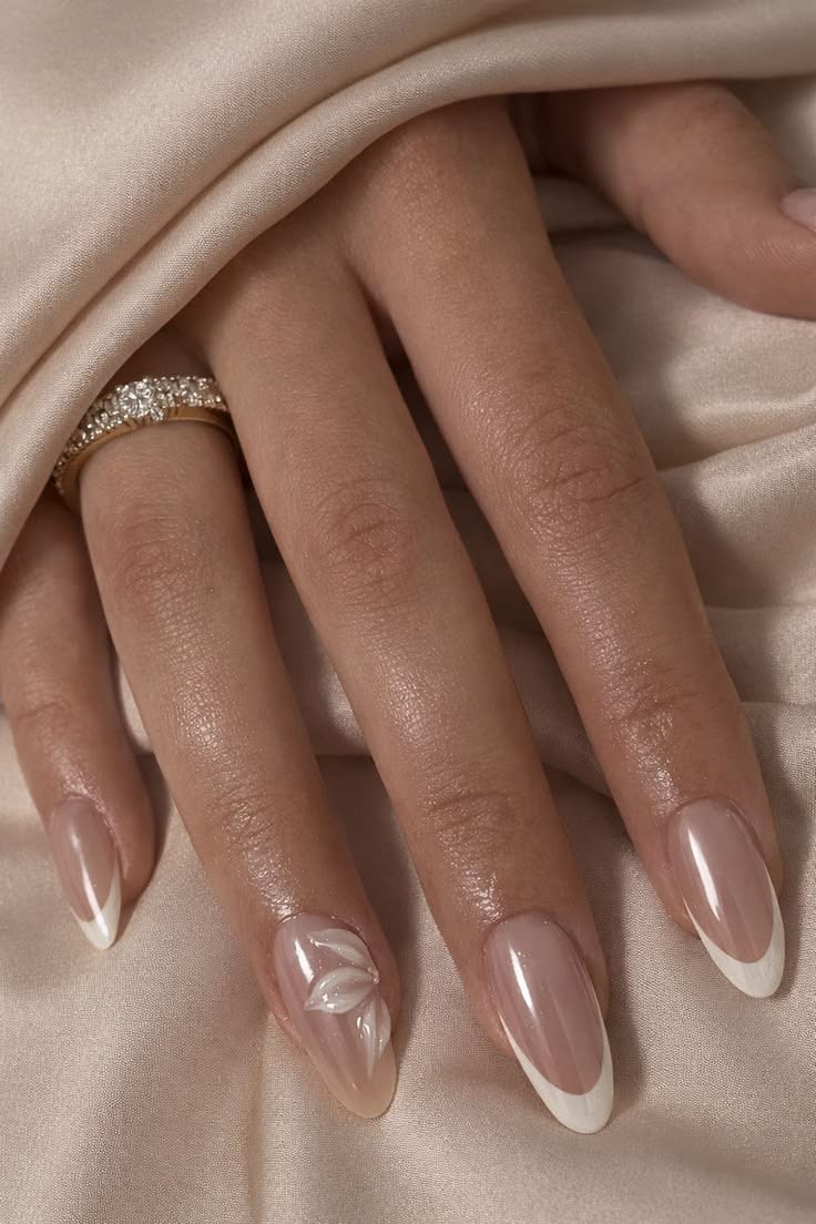 A hand with oval-shaped french tip acrylic nails. One nail with a 3D flower.