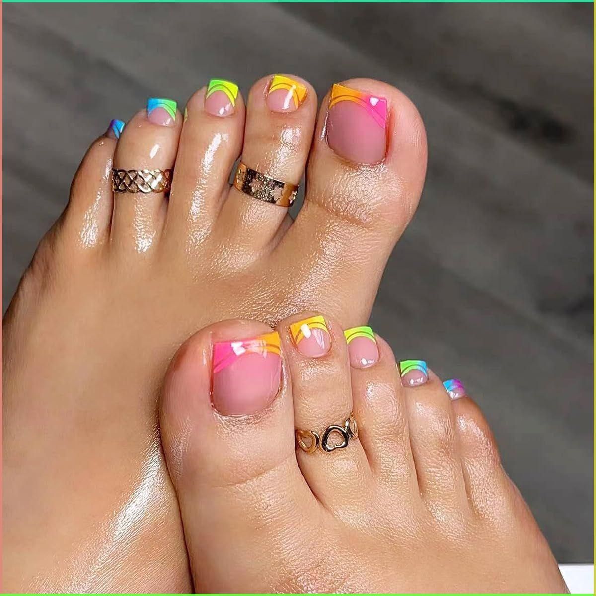 Close-up of a person's feet with brightly colored press-on toenails and decorative toe rings.