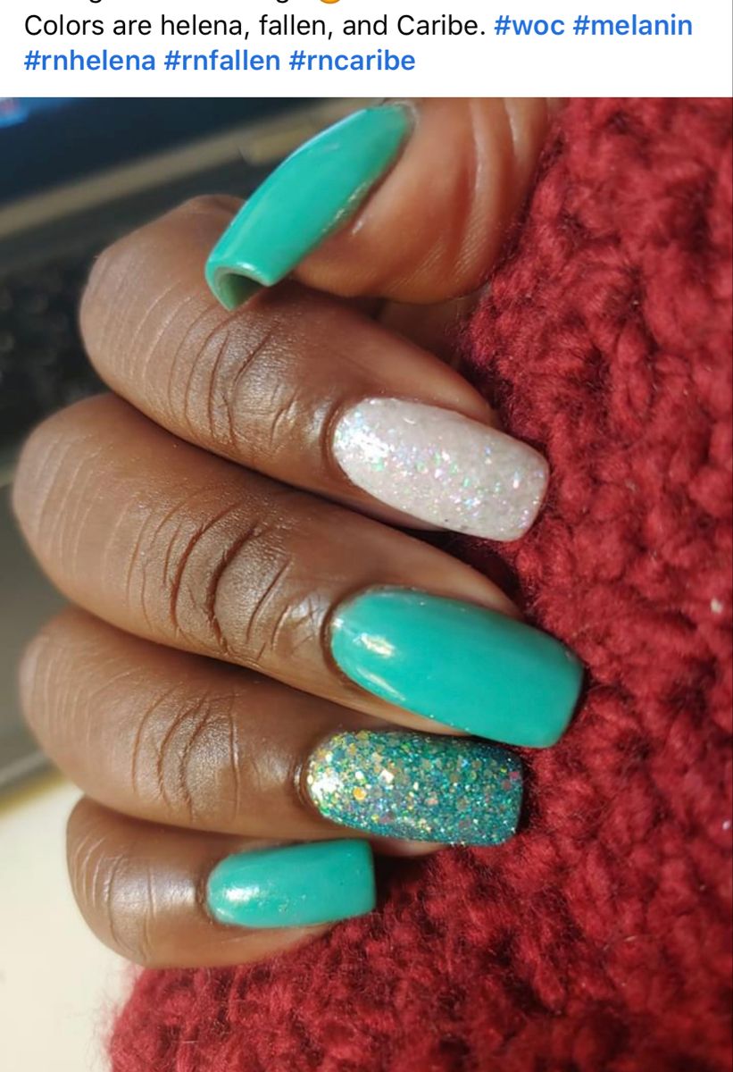 A hand with long, aqua-colored nails, some with glitter, resting on a fuzzy red surface.