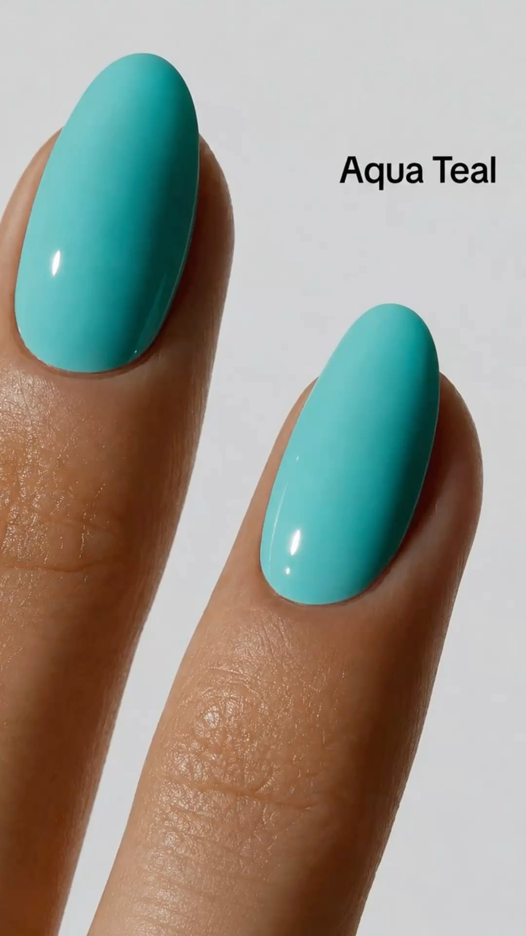 Close-up of two fingers featuring oval-shaped nails painted in a solid, glossy aqua teal color.