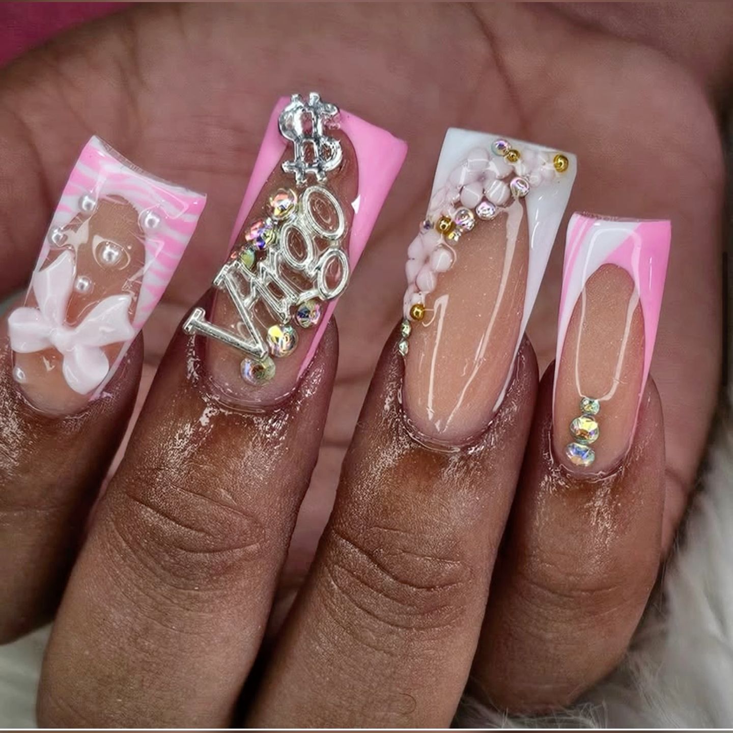 Close-up of four squared acrylic nails. From left, designs include a bow, a Virgo charm, a flower lattice, and a minimal…