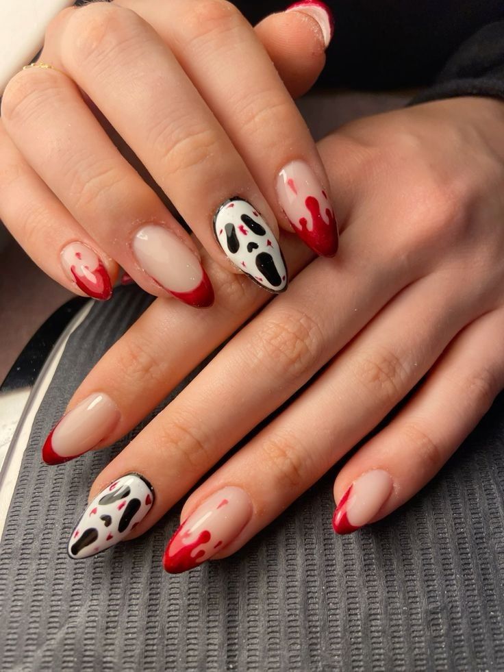 Close-up of hands with Halloween-themed nails, featuring ghost figures and red dripping designs.