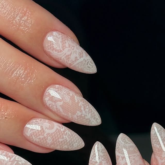 Close-up of manicured nails with white lace patterns over a nude base