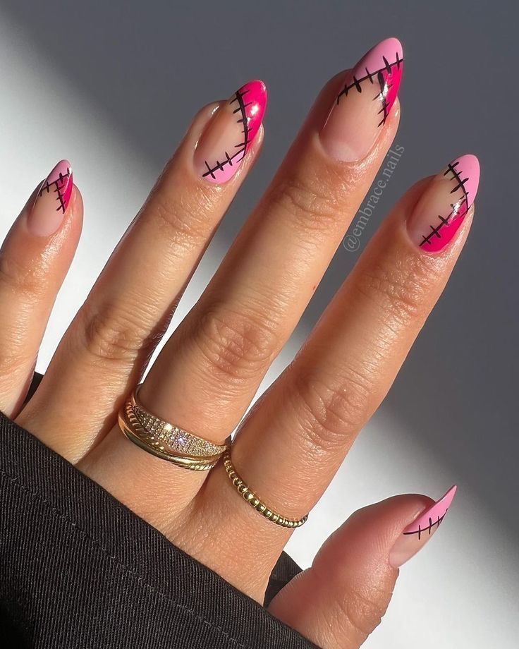 Close-up of a person's hand with almond-shaped nails featuring a stitched design in pink, magenta, and black thread-like…