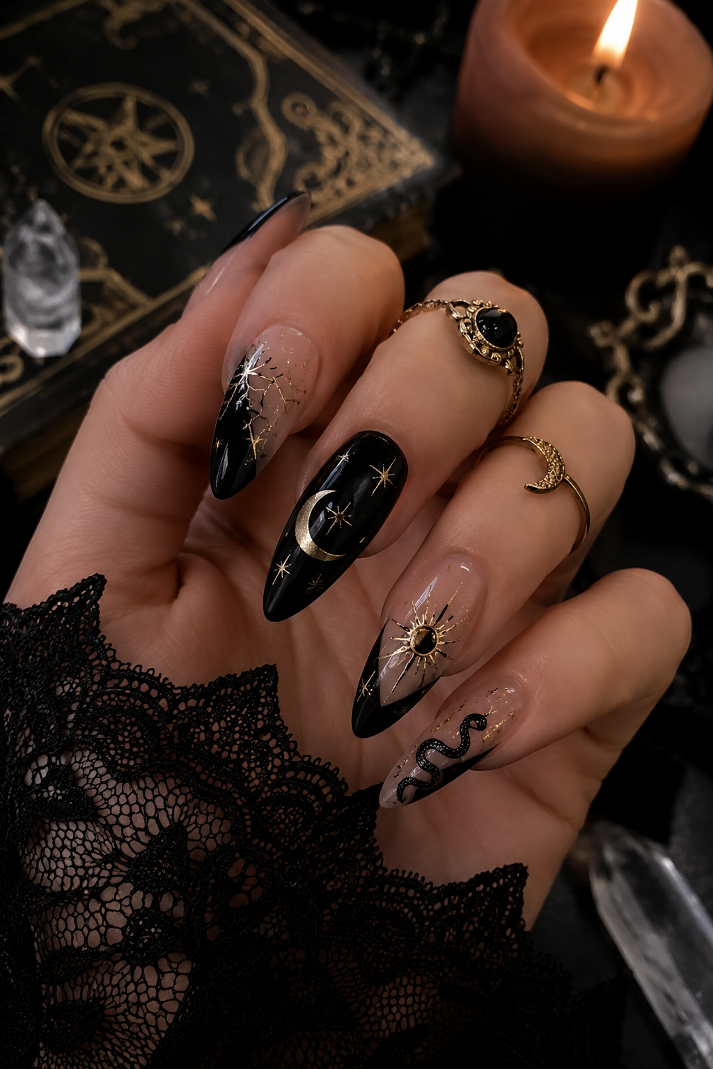 Pointed black and nude ombre nails with gold celestial elements and a black serpent design.