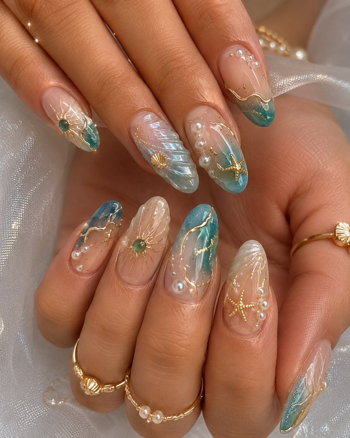 Close-up of fingernails with iridescent aqua and nude polish, adorned with gold lines, pearls, seashells, and starfish.