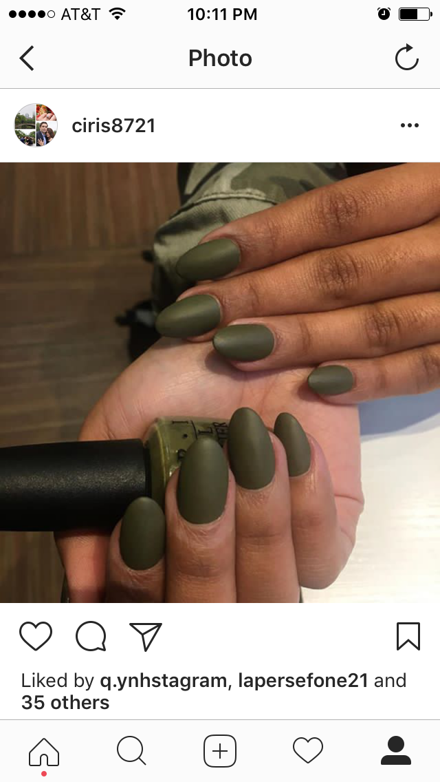 A person's hands display matte military green almond-shaped nails, holding a matching bottle of nail polish.