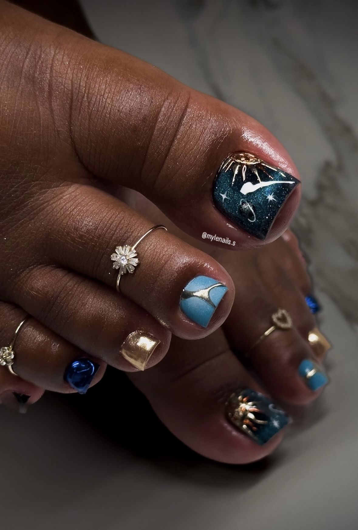 Close up of feet with dark blue and gold summer toe nail art, featuring star and planet designs.