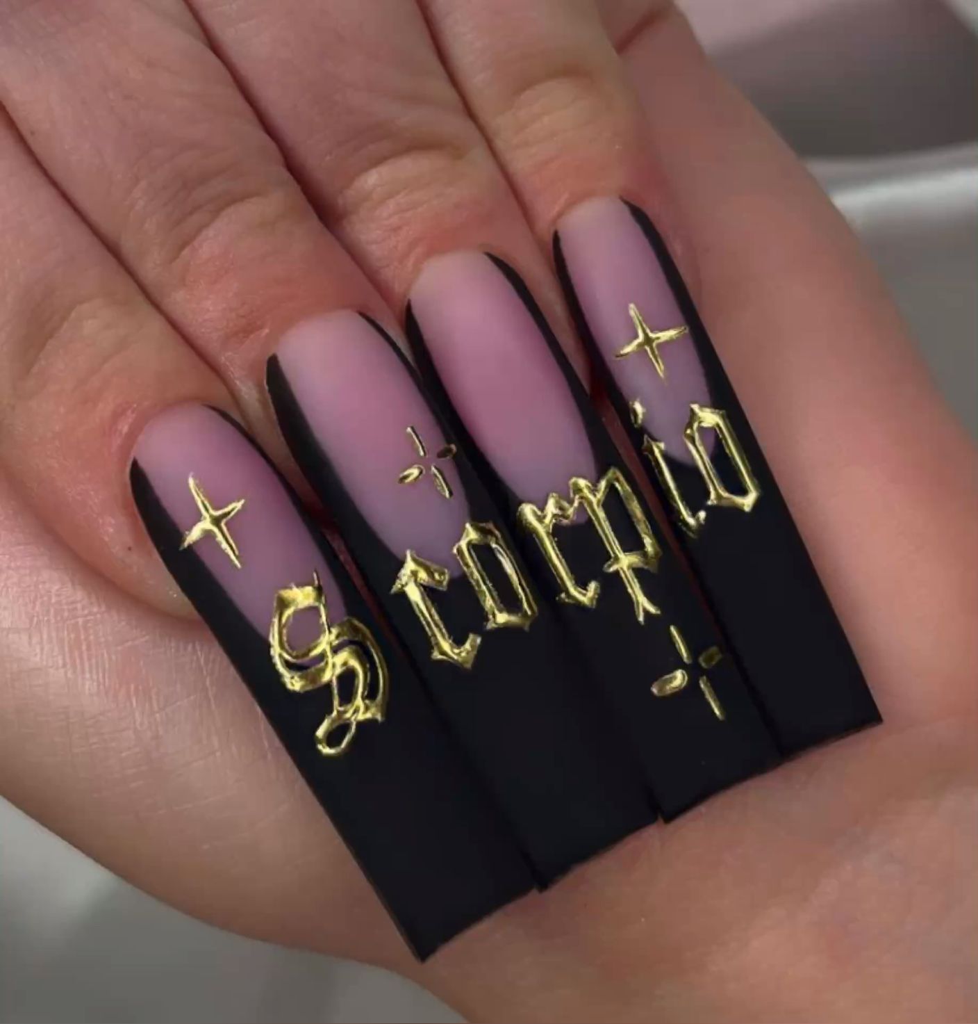 Close-up of long, coffin-shaped nails with black and subtle pink ombre.