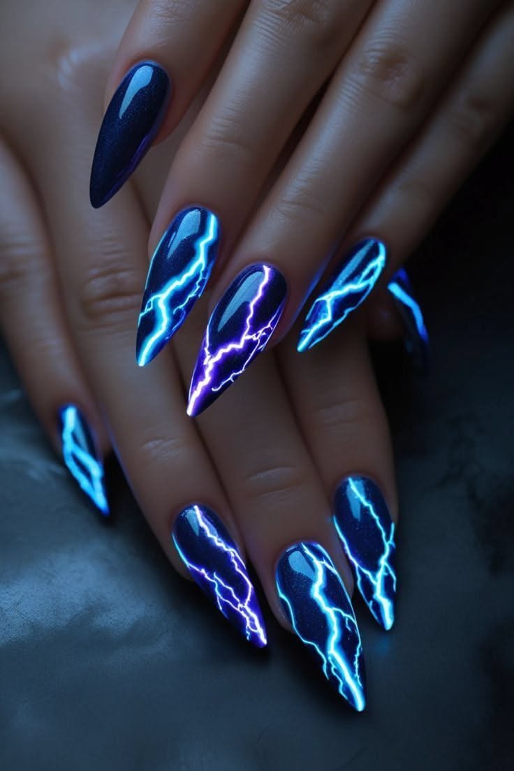 Dark blue nails with bright, glowing lightning bolt designs in blue and purple.