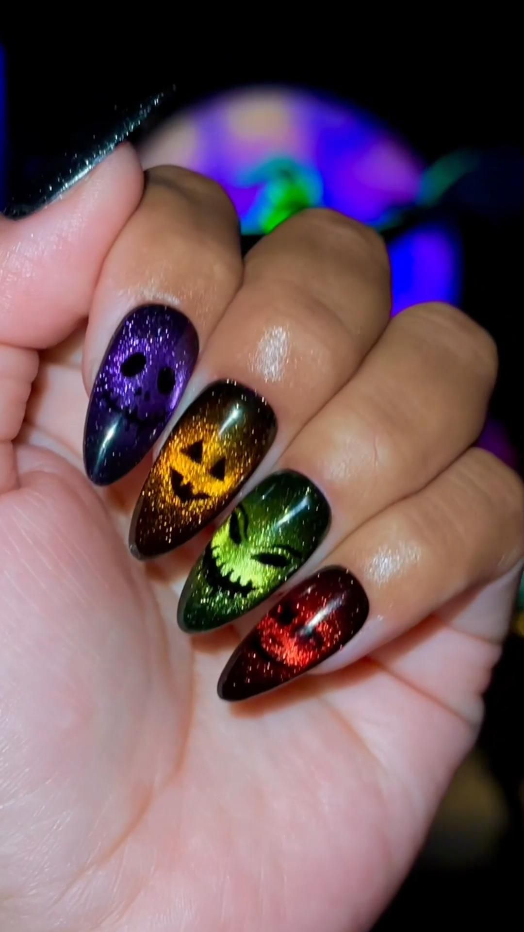 Close-up of fingernails with ombre glitter polish, each featuring a black jack-o'-lantern face.