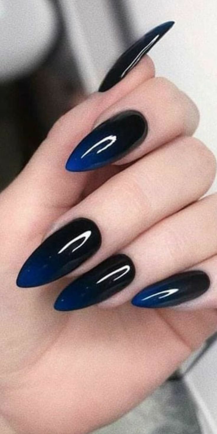 Hand with stiletto-shaped nails featuring a blue to black ombre gradient design.