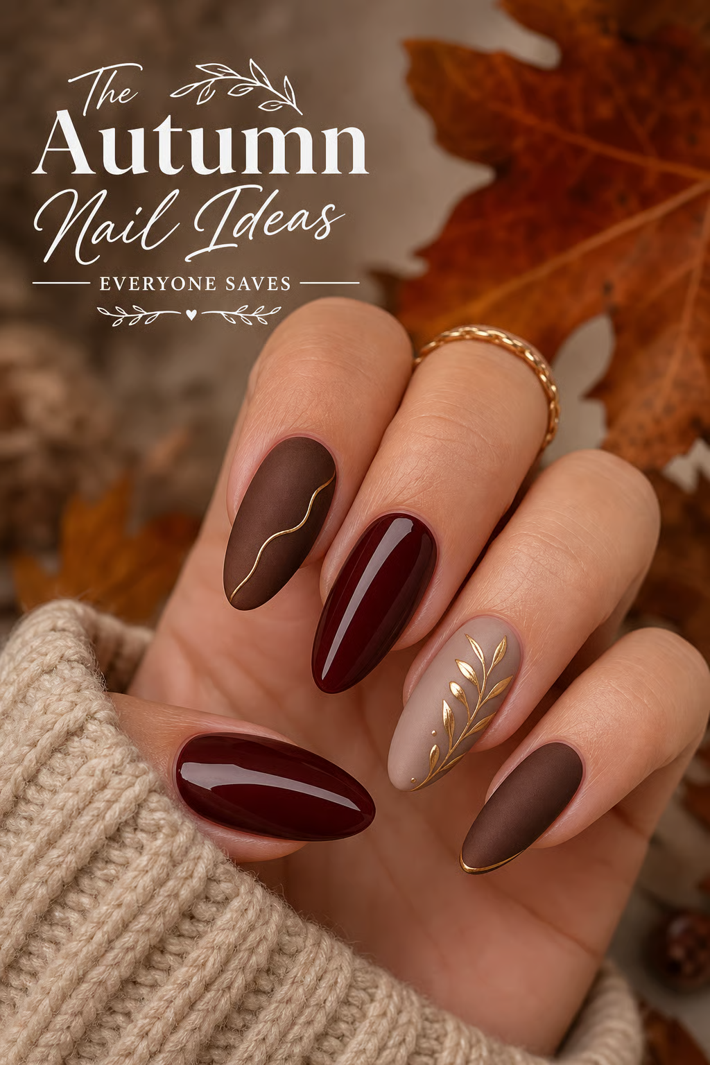 Hand with oval-shaped nails featuring matte brown, glossy deep red, and beige with gold leaf designs.