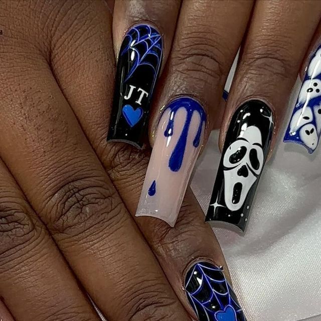 Long coffin-shaped nails with blue and black Halloween designs, including spiderwebs, a dripping pattern, and a Scream mask.