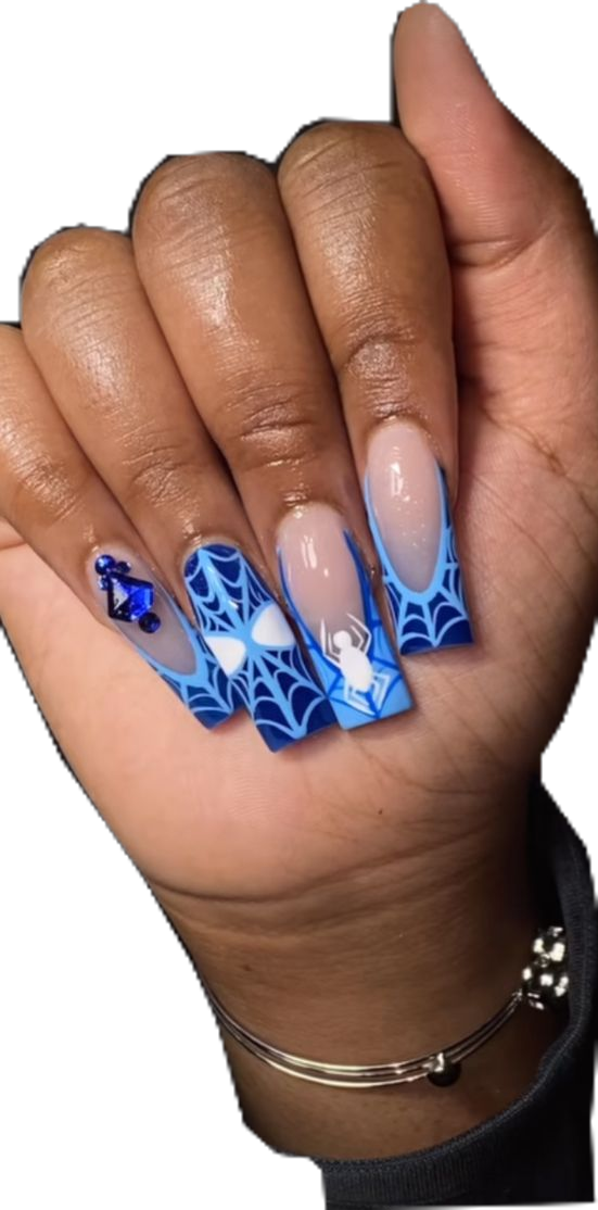Close-up of a hand with long blue and white nails featuring spider web designs, some with spider figures and blue gemstones.