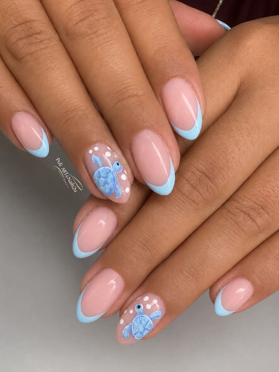 Close-up of manicured hands with short, oval nails. Most nails have a light pink base with a baby blue French tip.