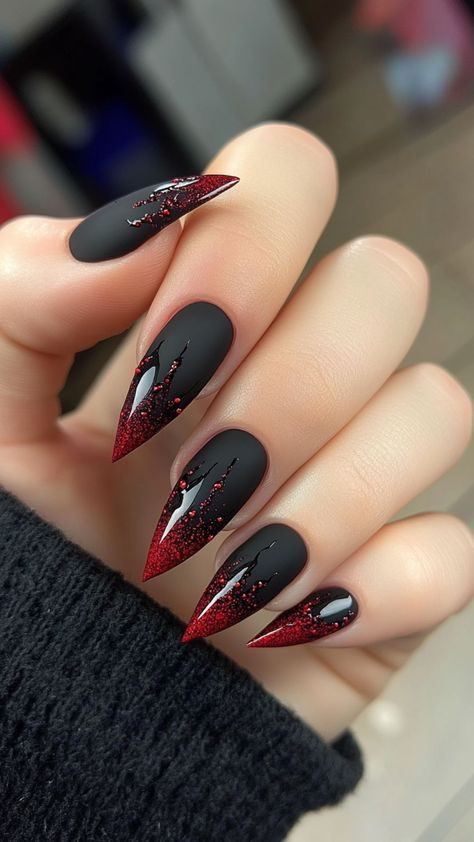 A hand displays matte black stiletto nails with glossy red glitter tips that appear to drip down the nail.