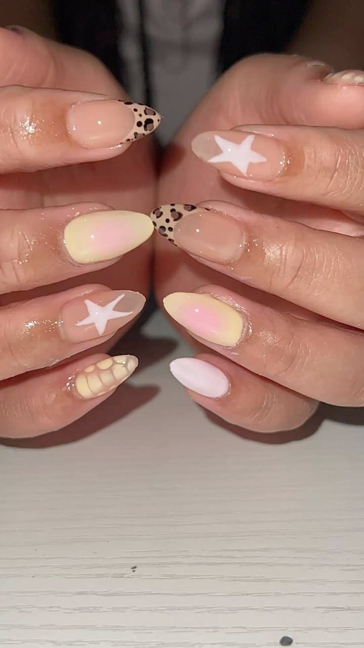 Close-up of manicured hands with various nail art designs, including leopard print tips, white stars, and pastel gradient…