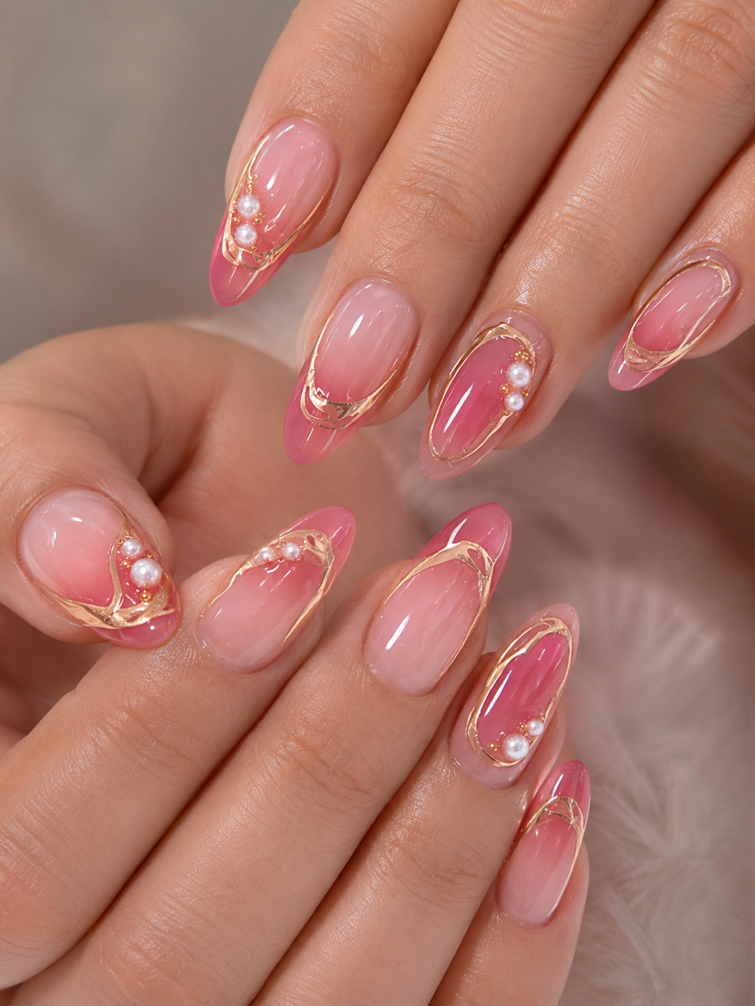 Close up of two hands with long, almond-shaped pink ombré nails.