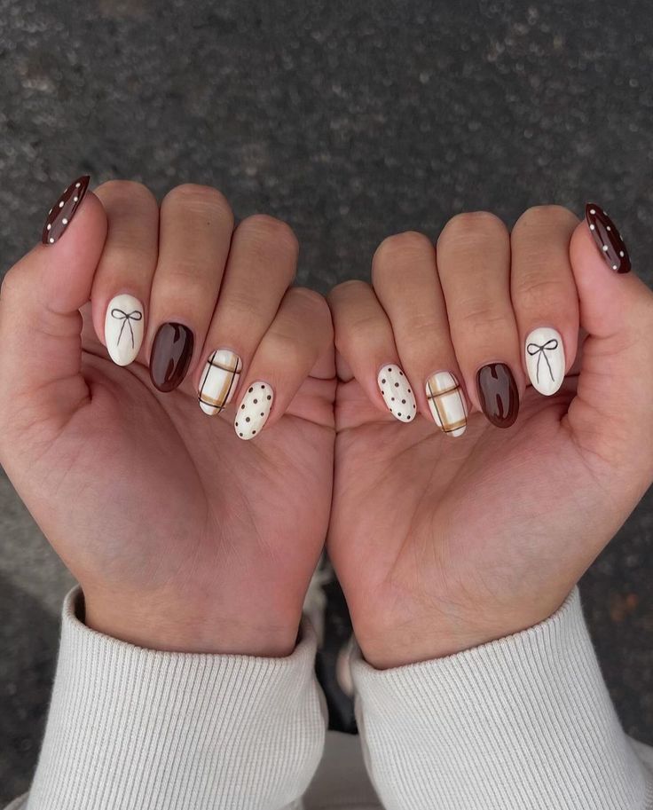 Two hands displaying almond-shaped nails with alternating designs in white, cream, and dark brown colors.
