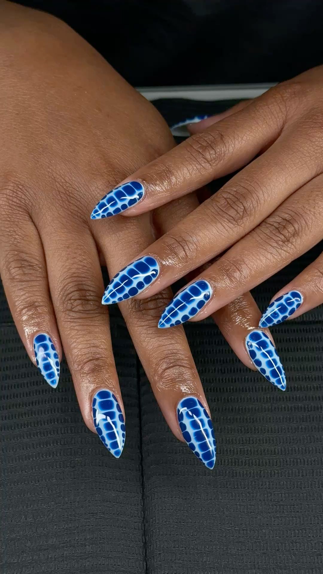 Close-up of hands with long, pointy blue nails featuring an alligator skin pattern.