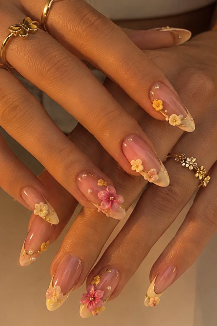 French tip manicure with 3D pink and yellow flowers and small pearl details on each nail.