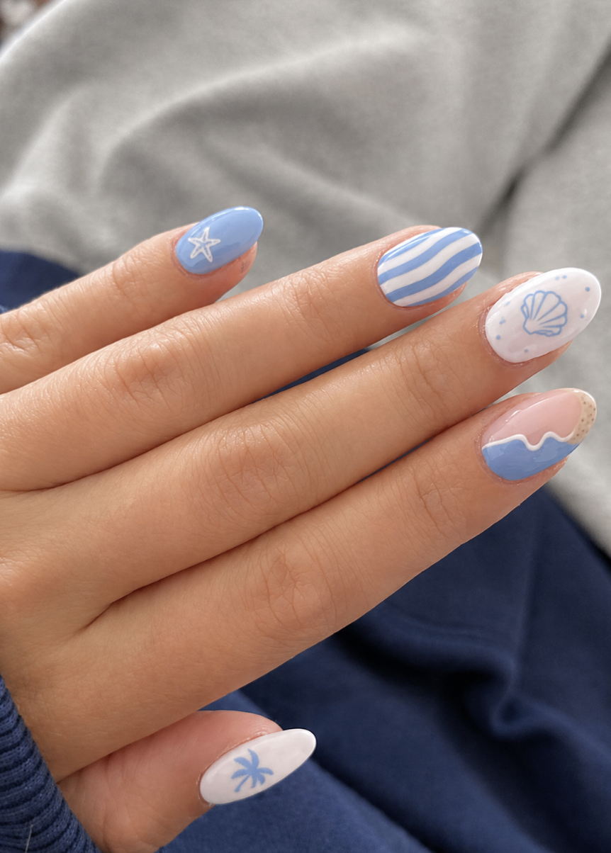 Close-up of a hand with nails painted with various summer-themed designs, including a starfish, waves, a seashell, and a…