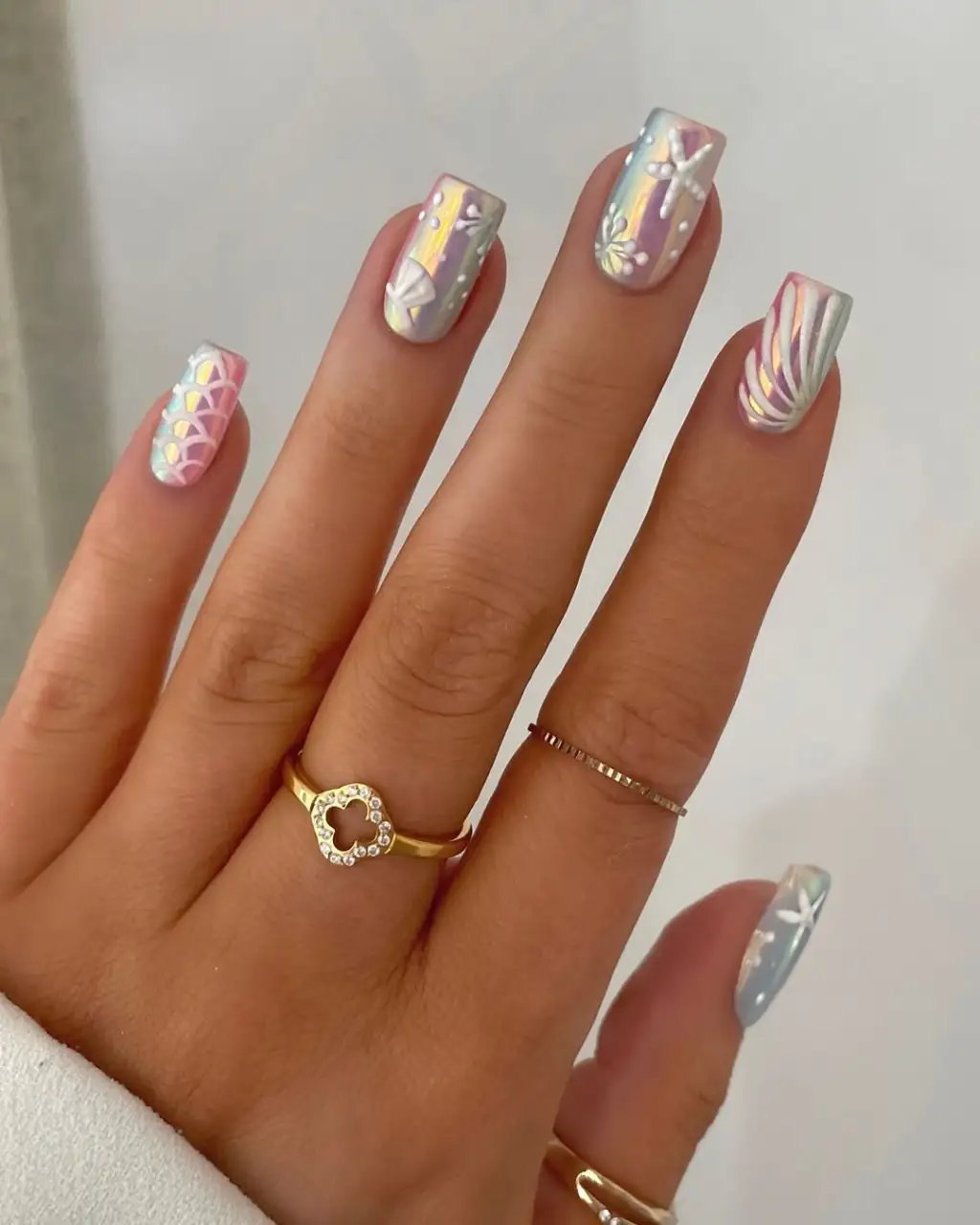 Short square nails in pale blue with pearly mermaid-inspired details