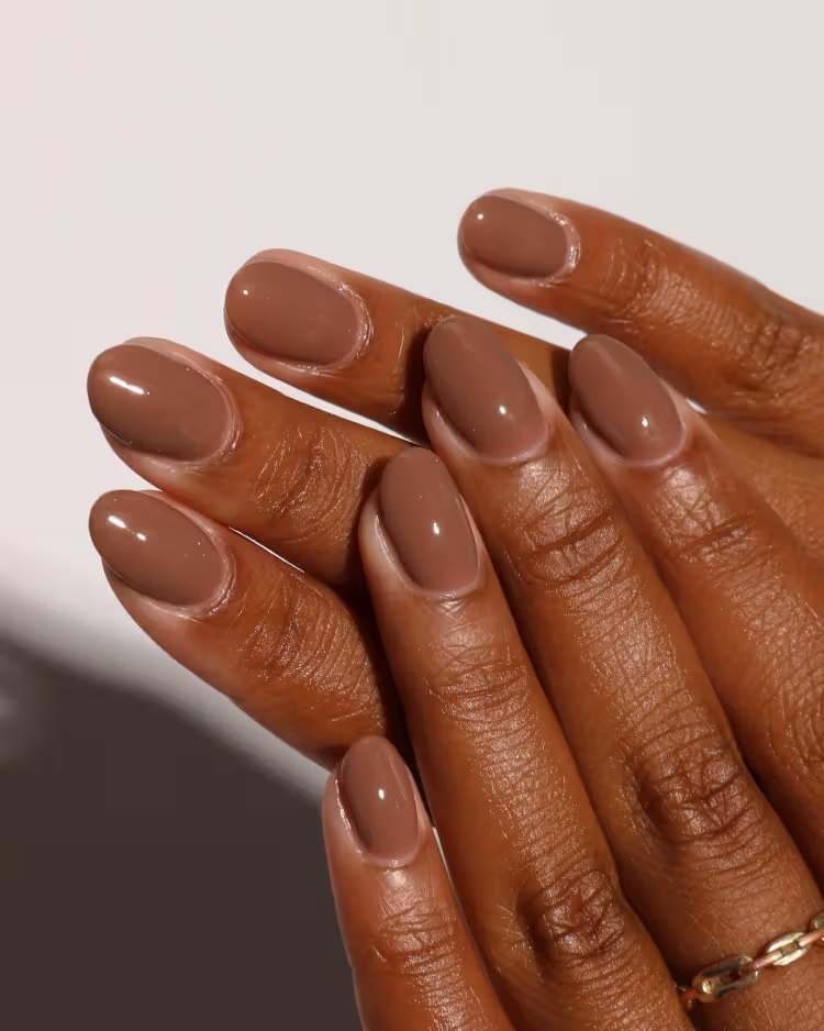 Short almond nails painted in a glossy medium brown shade.