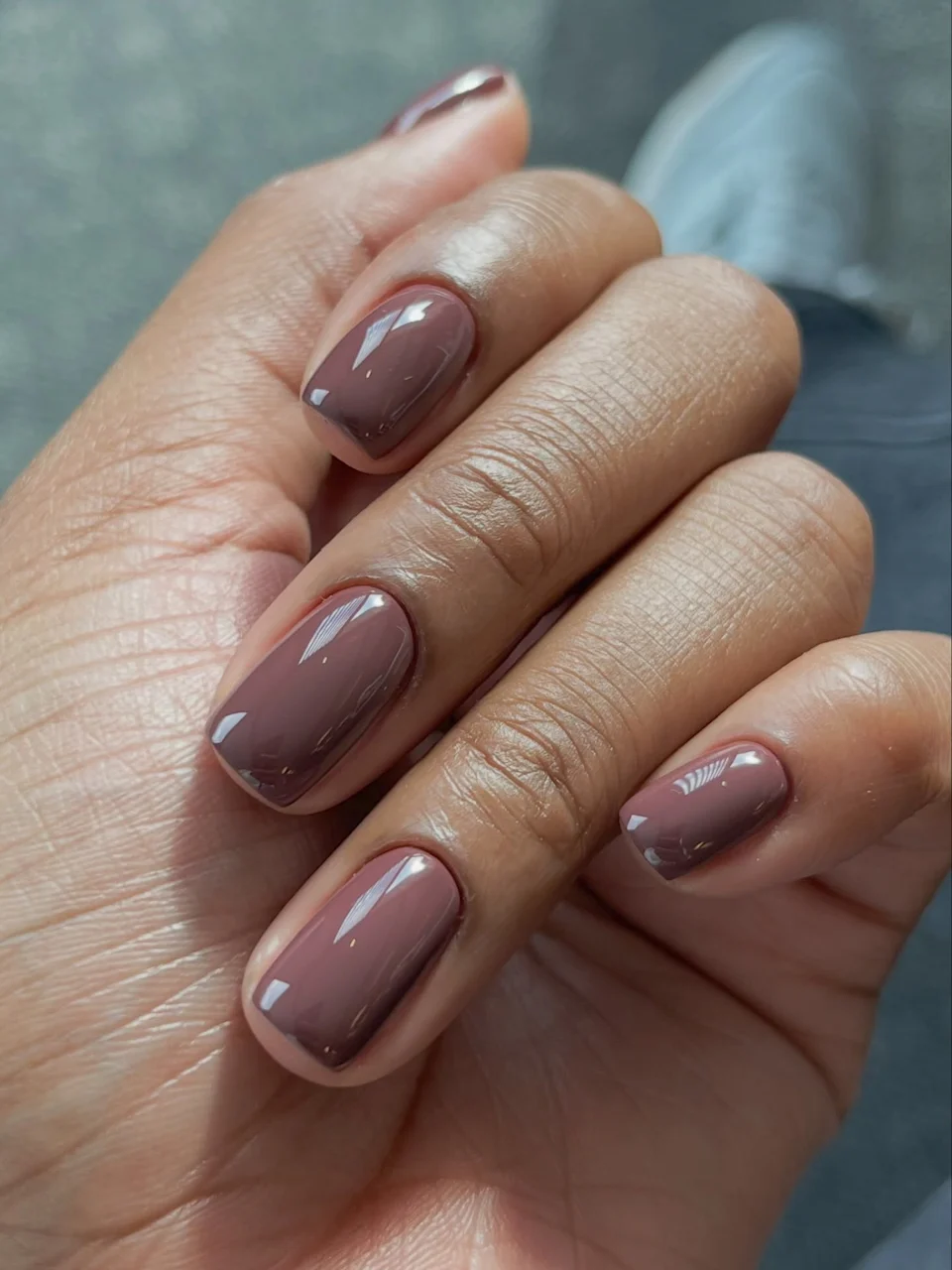 Brown manicure with glossy nails and small contrasting nail-art details.