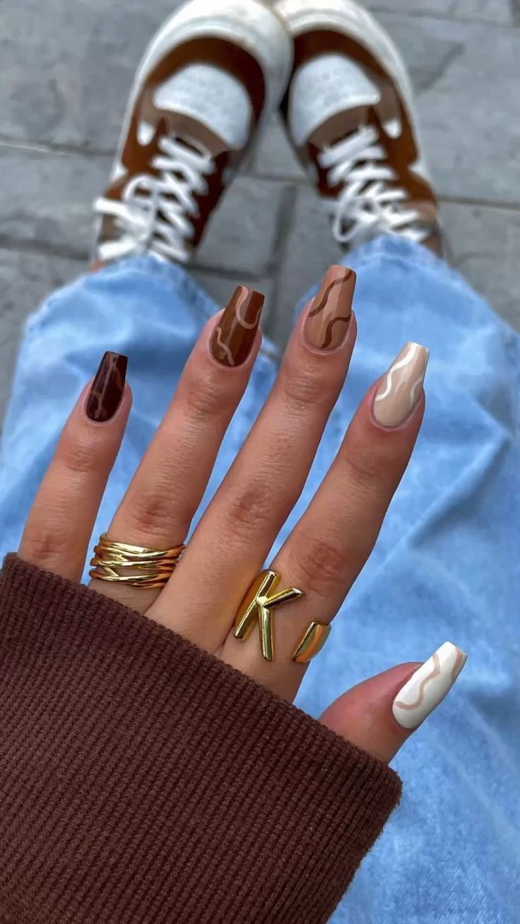 Brown French-tip nails with nude bases and almond-shaped extensions.
