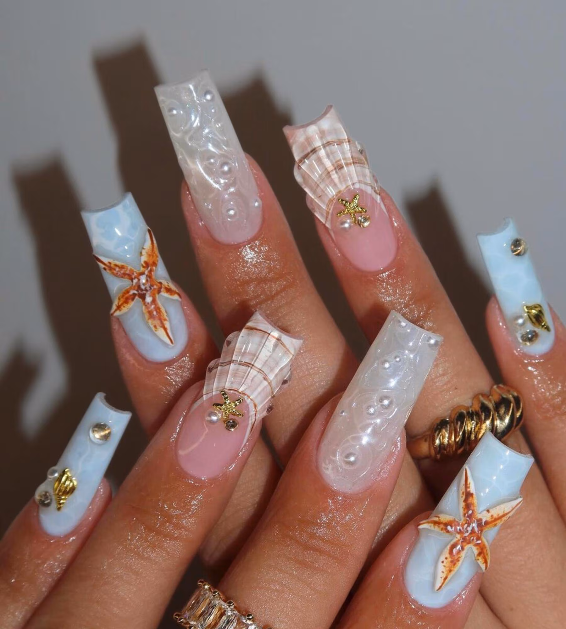 Long square press-on nails with blue details and raised starfish and shell decorations