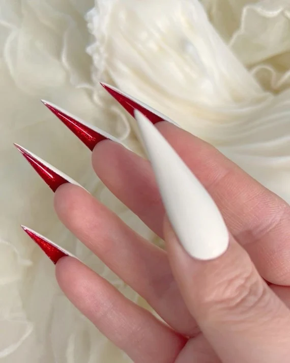 Long black stiletto press-on nails with red undersides and pointed tips.